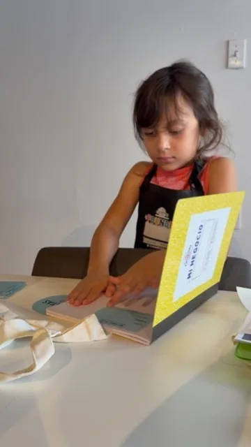 A girl in a studio apron works through her Mi Negocio workbook.