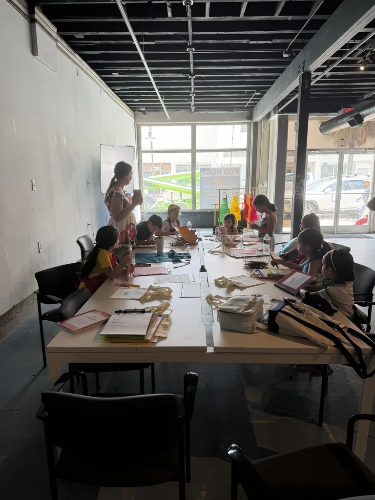 A wide view of the full first class in session, a mentor standing at the head of the table.